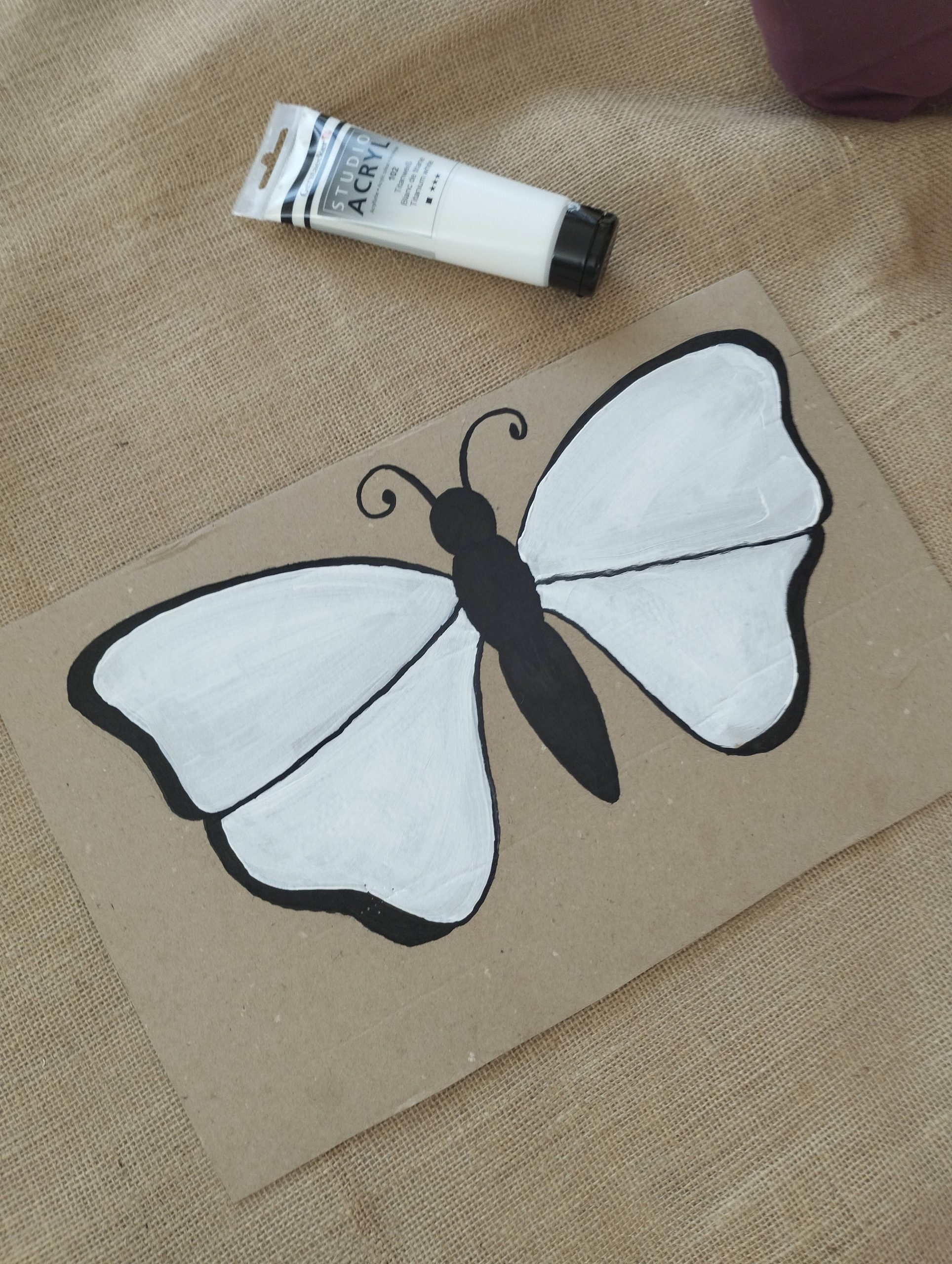 Peinture blanche d’un papillon en carton pour activité de printemps en maternelle